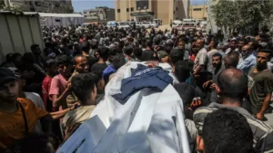 Le corps d'un journaliste, surmonté de son gilet de protection, transporté lors d'une cérémonie dans la cour de l'hôpital Nasser de Khan Younès, dans la bande de Gaza, lundi 25 août. (ABED RAHIM KHATIB / ANADOLU / AFP)